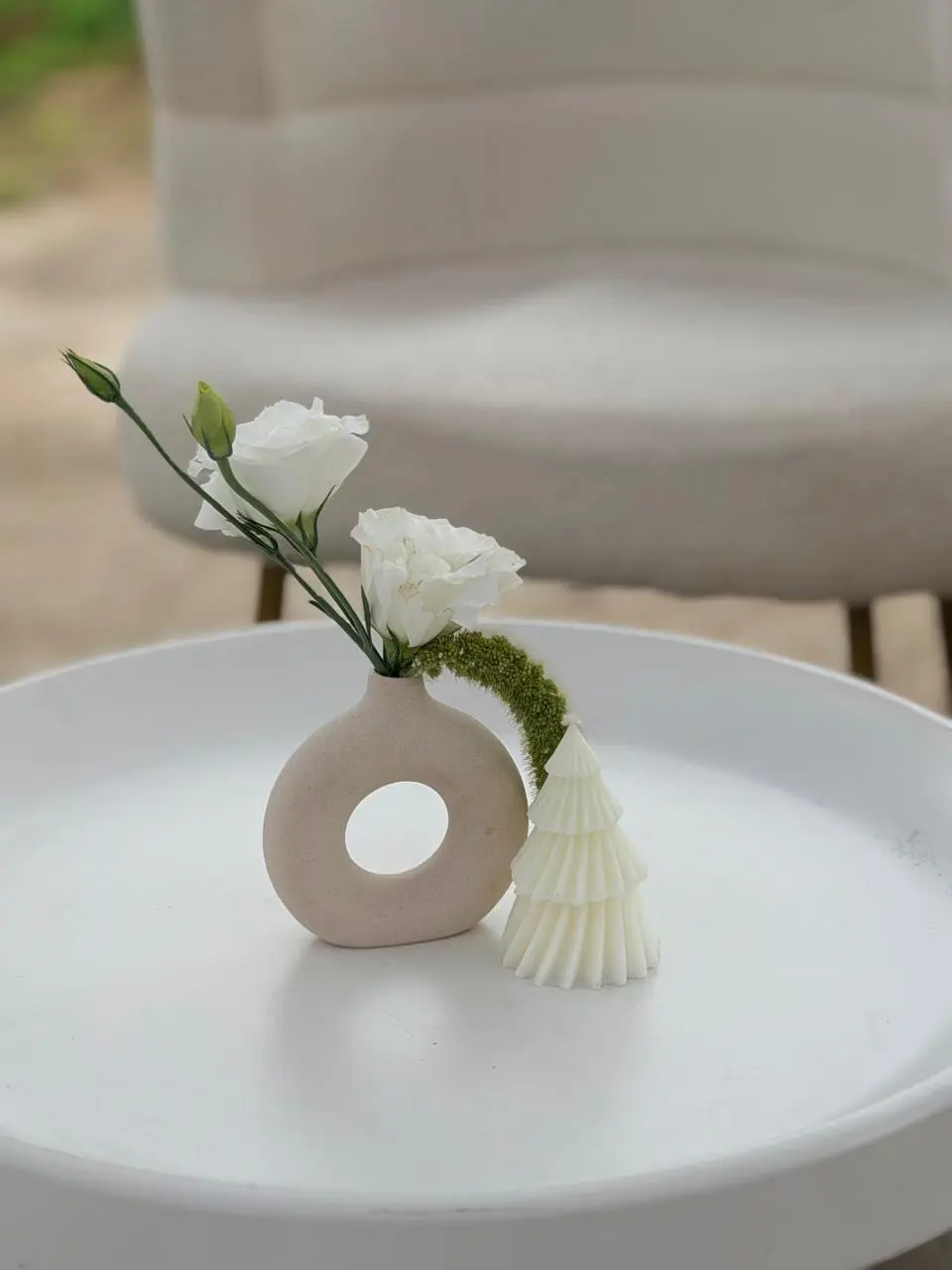 Home decor of a vase with a plant inside and a pine tree candle beside it.  
